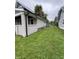 View of the side yard, showcasing the home's siding, brick foundation, and spacious lawn area to the side at 3526 Evergreen Ave, Indianapolis, IN 46205