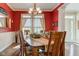 Elegant dining room with hardwood floors, red walls, and a chandelier over a large dining table at 3533 Alexandria Pike, Anderson, IN 46012