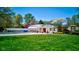 Charming building featuring a red door, green roof, and surrounded by lush greenery and vibrant landscaping at 3533 Alexandria Pike, Anderson, IN 46012