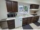 Kitchen with dark wood cabinets, light countertops, stainless microwave and white appliances at 404 E Madison St, Alexandria, IN 46001