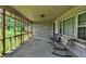 Enclosed porch with seating, providing a cozy outdoor space with views of the well-manicured lawn and garden at 4125 S Post Rd, Indianapolis, IN 46239