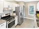 Modern kitchen featuring stainless steel appliances, white cabinets, and a tile backsplash offers a clean aesthetic at 4345 Guilford Ave, Indianapolis, IN 46205