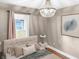 Cozy bedroom featuring a decorative chandelier, neutral tones, and a large window with soft, natural light at 4345 Guilford Ave, Indianapolis, IN 46205