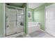 Bathroom featuring light green walls, a shower, a tub, and a white door for easy access at 4683 W Lawrence Way, New Palestine, IN 46163