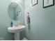 Small powder room features a pedestal sink, round mirror and light blue walls at 4683 W Lawrence Way, New Palestine, IN 46163