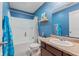 This bathroom features blue walls, a shower-tub combo, a dark wooden vanity, and neutral countertops at 4683 W Lawrence Way, New Palestine, IN 46163