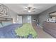 Spacious bedroom with gray walls, a ceiling fan, and a bed with multiple pillows beneath a green blanket at 4683 W Lawrence Way, New Palestine, IN 46163