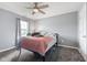 Light grey bedroom with a large bed beneath a ceiling fan and a window that overlooks green tree branches at 4683 W Lawrence Way, New Palestine, IN 46163
