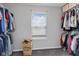 Walk-in closet with shelving and hanging storage on either side of a single window with closed blinds at 4683 W Lawrence Way, New Palestine, IN 46163