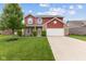 Charming two-story home with brick and red siding, attached garage, and well-manicured lawn at 4683 W Lawrence Way, New Palestine, IN 46163