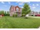 Inviting front yard with lush green grass and mature tree, complementing the charming red home at 4683 W Lawrence Way, New Palestine, IN 46163