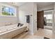 Bathroom featuring a soaking tub with tile surround, barn door and window at 4808 Lakeview Dr, Greenwood, IN 46143