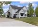 Side angle of a white farmhouse exterior with lush landscaping and concrete driveway under a cloudy sky at 4808 Lakeview Dr, Greenwood, IN 46143