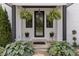 Front door with stylish hanging ferns and planters on a charming covered porch with white brick at 4808 Lakeview Dr, Greenwood, IN 46143