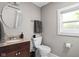 Bathroom features a granite vanity, toilet, round mirror and natural lighting at 4818 Winthrop Ave, Indianapolis, IN 46205