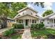 Charming two-story home with a welcoming front porch, lush landscaping, and a vibrant green front door at 4818 Winthrop Ave, Indianapolis, IN 46205