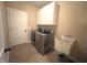 A spacious laundry room with modern washer and dryer, tiled floors, and utility sink at 5010 Cabrillo Dr, Plainfield, IN 46168