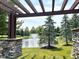 Beautiful pond view featuring a fountain and lush landscaping, as seen from under a pergola at 5010 Cabrillo Dr, Plainfield, IN 46168
