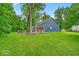 Lush backyard with a well-maintained lawn and a cozy stone patio featuring a fire pit and seating at 5558 Spicebush Dr, Indianapolis, IN 46254