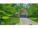 Charming brick home with a blue garage door, a well-manicured lawn, and mature trees providing shade at 5558 Spicebush Dr, Indianapolis, IN 46254