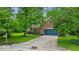Beautiful brick home featuring a blue garage door, green lawn, and mature trees in a serene setting at 5558 Spicebush Dr, Indianapolis, IN 46254