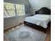 Sunlit bedroom showcasing a large dark wood bedframe, hardwood floors, and a patterned area rug at 5889 Crestview Ave, Indianapolis, IN 46220