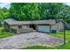 Aerial view of a stone ranch home featuring a two-car garage, mature trees, and a stone wall surrounding the front yard at 741 Fairway Dr, Indianapolis, IN 46260