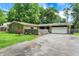 Stone ranch home featuring a two-car garage, mature trees, and a stone wall surrounding the front yard at 741 Fairway Dr, Indianapolis, IN 46260
