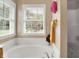 Serene bathroom showcasing a soaking tub with a tile surround and two bright, window views at 7521 Kilbarron Cir, Indianapolis, IN 46217