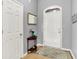 Neutral entryway featuring a front door with transom window, half-round table, and light wood floors at 7521 Kilbarron Cir, Indianapolis, IN 46217