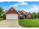 Charming single-story red brick home featuring an attached two-car garage and lush green lawn at 7521 Kilbarron Cir, Indianapolis, IN 46217