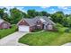 Well-manicured front yard with beautiful landscaping and a charming brick house with a two-car garage at 7521 Kilbarron Cir, Indianapolis, IN 46217
