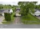 Front of house aerial view featuring a neatly landscaped yard, mature trees, and a paved driveway at 7724 Blackthorn Dr, Indianapolis, IN 46236