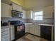 Efficient kitchen featuring white cabinets, black appliances, and a stainless steel microwave at 7724 Blackthorn Dr, Indianapolis, IN 46236