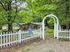 View of home behind white picket fence and decorative archway at 8310 Dog Trot Ln, Morgantown, IN 46160