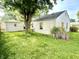 Exterior backyard view with green grass, a tree and the side of the house with a detached garage at 910 Lonsvale Dr, Anderson, IN 46013