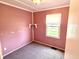 Bedroom featuring soft pink walls, carpet, and a window, providing a calming and inviting space at 910 Lonsvale Dr, Anderson, IN 46013