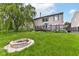A spacious backyard featuring a stone fire pit, large willow tree, and wooden deck at 9358 W Rising Sun Dr, Pendleton, IN 46064