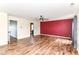 Bright living room with laminate flooring, a red accent wall, and ceiling fan at 9358 W Rising Sun Dr, Pendleton, IN 46064