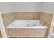 A well-lit bathroom with a jacuzzi tub, tiled wall and wood laminate flooring at 9754 Bradford Knoll Dr, Fishers, IN 46037