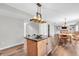 Open-concept kitchen with a central island and granite countertops, flowing into a dining area with a stone fireplace at 9754 Bradford Knoll Dr, Fishers, IN 46037
