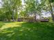 Large, sunny backyard featuring lush green lawn, large trees, and wooden deck, great for outdoor activities at 10307 Wilson Rd, Brownsburg, IN 46112