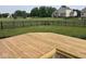 Wooden deck in a backyard with a black fence, lush green grass, and neighborhood views at 1287 Highland Lake Way, Brownsburg, IN 46112