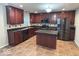 Stylish kitchen boasts cherry wood cabinets, stainless steel appliances, tile backsplash, and central island at 1287 Highland Lake Way, Brownsburg, IN 46112