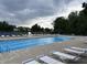 Bright blue community pool with rows of lounge chairs and a lifeguard stand against a backdrop of trees and cloudy skies at 1287 Highland Lake Way, Brownsburg, IN 46112