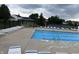 Community pool with lounge chairs, sun shade, and mature trees on a cloudy day at 1287 Highland Lake Way, Brownsburg, IN 46112