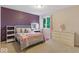 Inviting bedroom with a purple accent wall and a vanity area illuminated by natural light at 12961 Limberlost Dr, Carmel, IN 46033