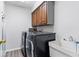 Functional laundry room with modern washer and dryer, storage cabinets, and utility sink at 12961 Limberlost Dr, Carmel, IN 46033