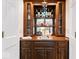 This wet bar features wood cabinets, a sink, mirror backsplash, and glass shelving for a luxurious entertaining space at 12961 Limberlost Dr, Carmel, IN 46033