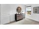 Bright bedroom featuring a wooden dresser, round mirror, and neutral carpet, with a view from the window at 15387 Alperton Rd, Fishers, IN 46037